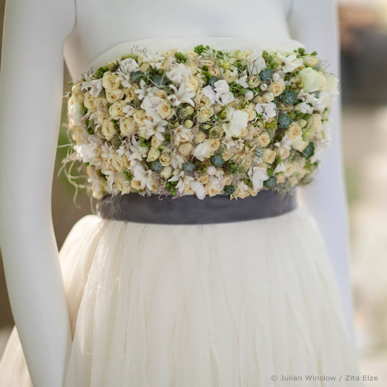 detail of the top of  gown adorned with whit, yellow and green flowers and natural elements