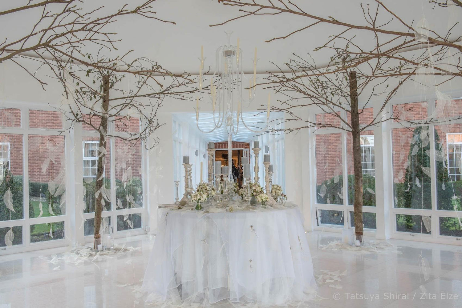 White table cloth on a decorated round table with flowers in the middle of a white room